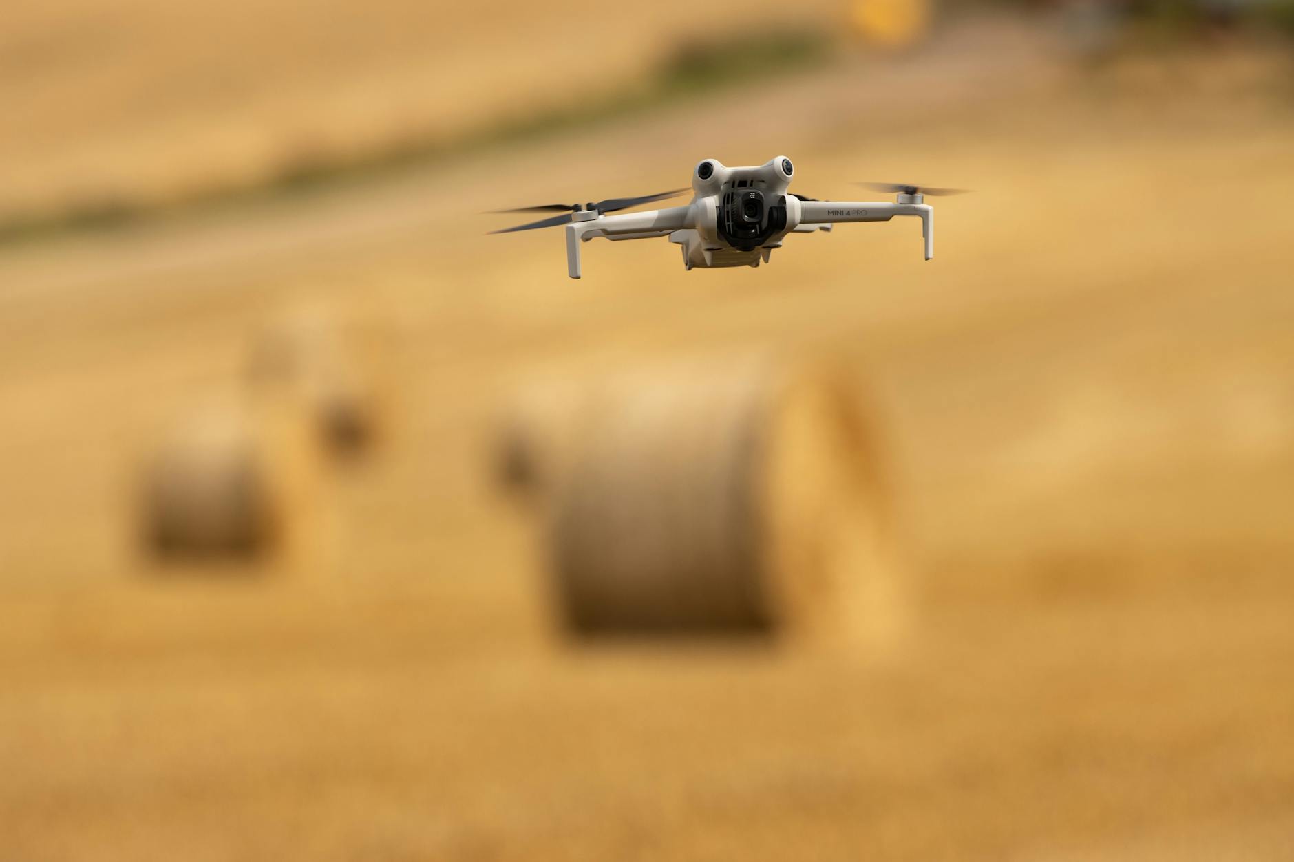 A drone captures scenic views of hay bales in a sunny Swedish wheat field.