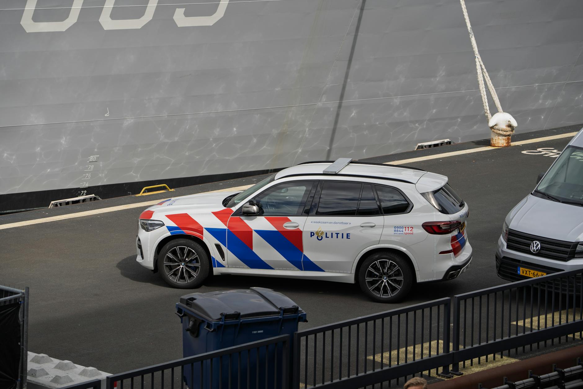 Dutch police vehicle parked near a large ship at a dock, showcasing maritime security presence.