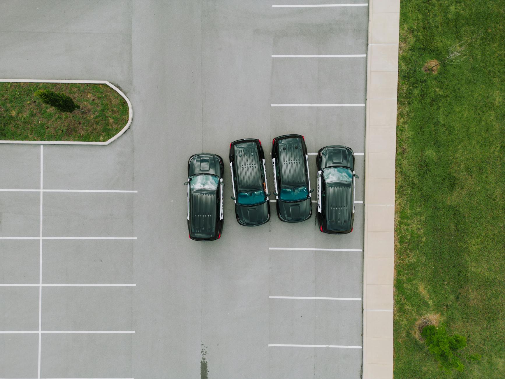 Top-down drone shot of police vehicles parked in an empty parking lot with green grass.