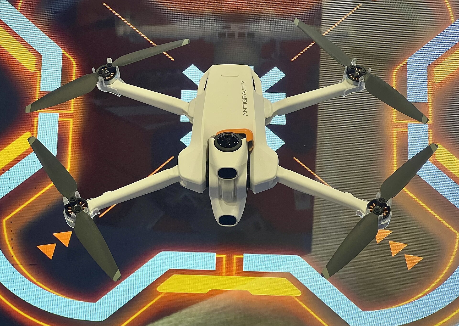 Kompakt hvit 360-graders drone med to runde kameralinser, ved siden av VR-briller mot nøytral bakgrunn.
