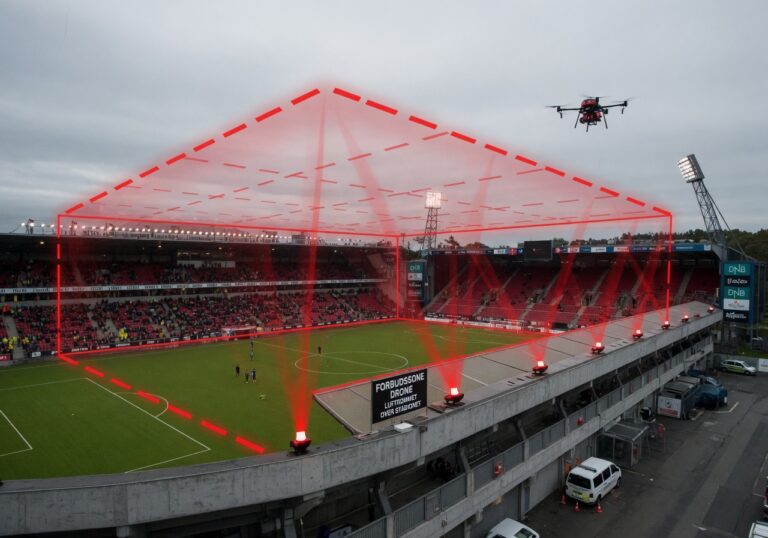 Fotballstadion sett ovenfra med markert forbudssone rundt arenaen. Illustrasjon av droneforbud.