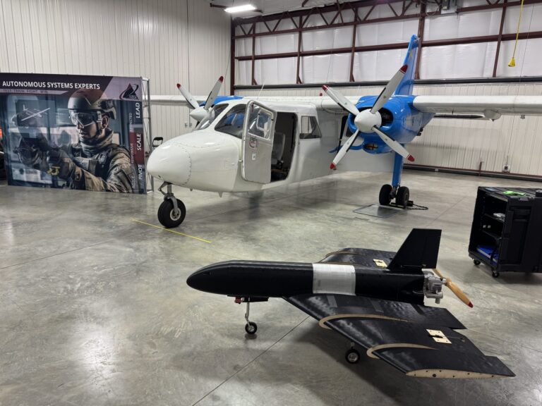 Svart fastvinget måldrone i ABSIs hangar med fly i bakgrunnen