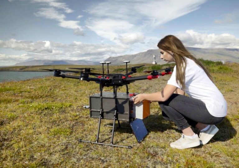 Leveringsdrone med pakke lastes på bakken av en person.