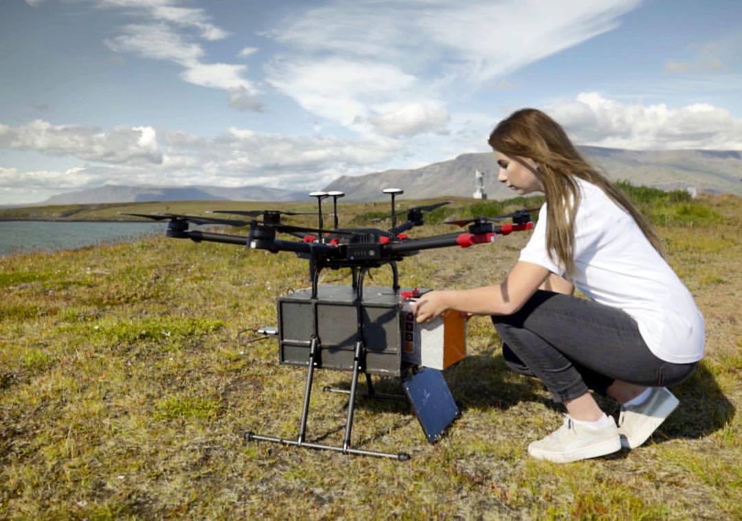 Leveringsdrone med pakke lastes på bakken av en person.