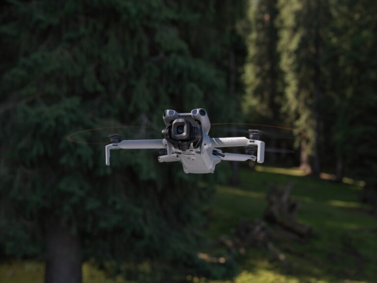 DJI Mini 5 Pro i lav flukt foran skog, kompaktdrone under 250 gram