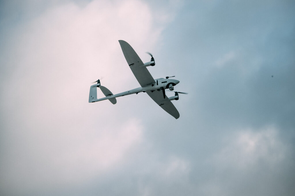 Quantum Systems Vector, en VTOL-fastvingedrone med to rotorbommer, i flukt mot en overskyet himmel
