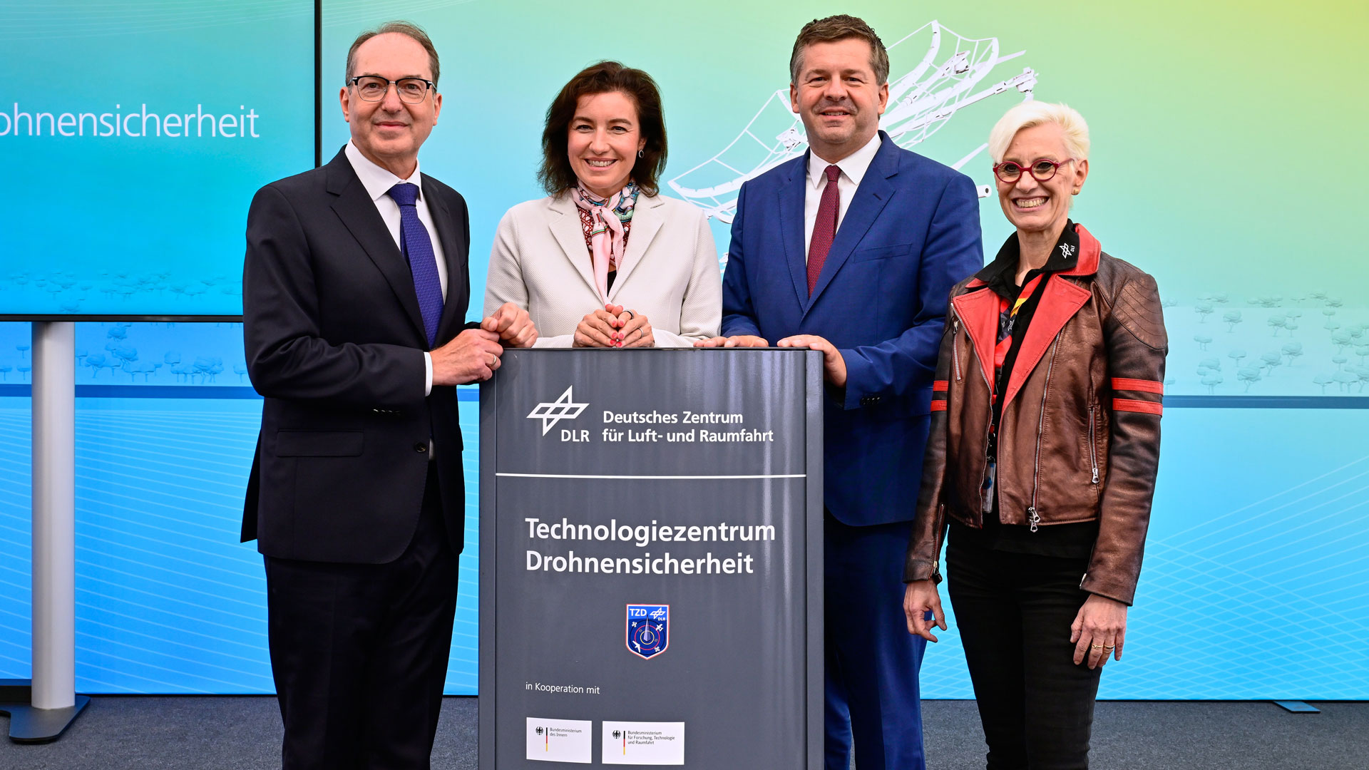 Fire personer står ved et skilt med teksten Technologiezentrum Drohnensicherheit ved åpningen i Cochstedt