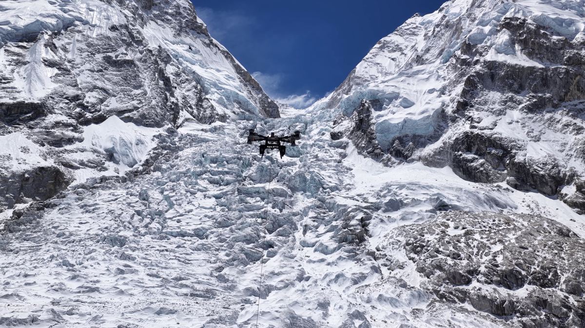 Leveringsdrone med hengende last over isbre og snødekte fjellsider på Everest
