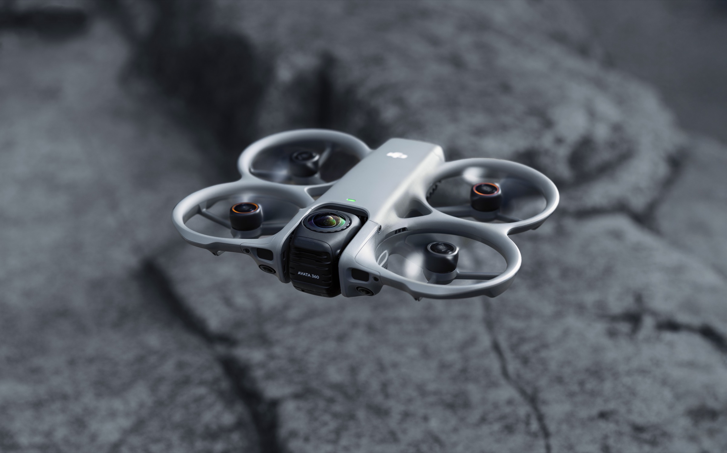 Kompakt FPV-drone med propellbeskyttelse og kulerundt 360-kamera på toppen, mot nøytral bakgrunn