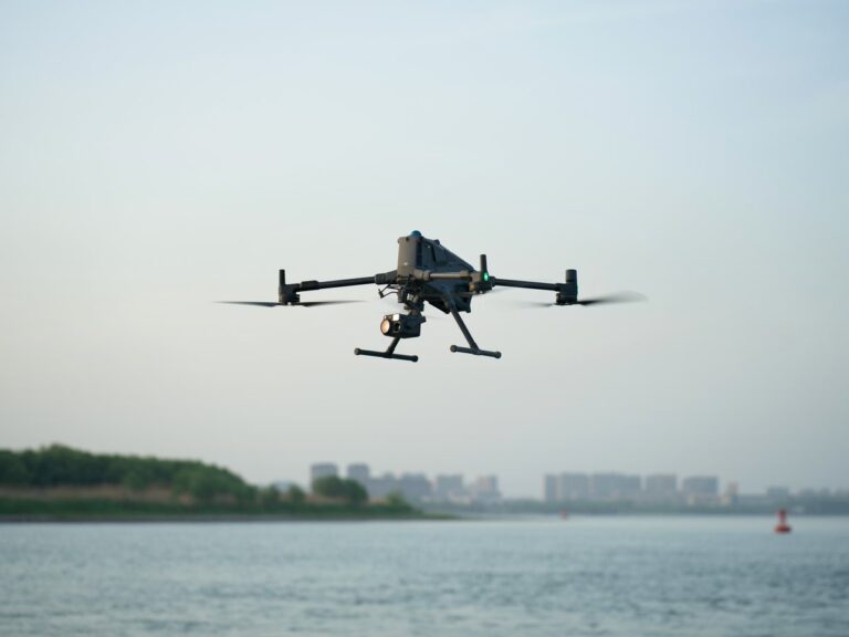 DJI Matrice 400 industridrone i flukt over vann med bybebyggelse i bakgrunnen