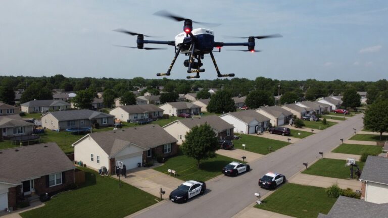 Politidrone i luften over boligstrøk med politibiler synlig på bakken.