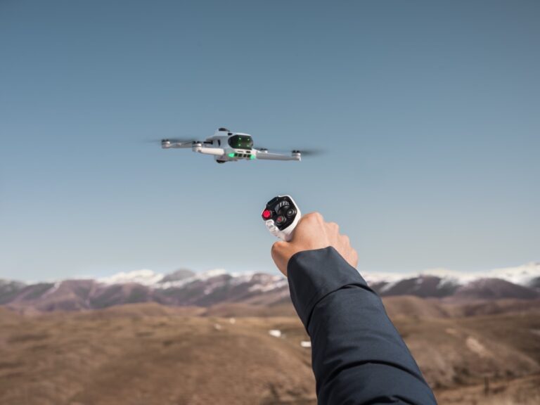 Antigravity A1-drone i lufta over fjellandskap, styrt med en håndholdt bevegelseskontroller