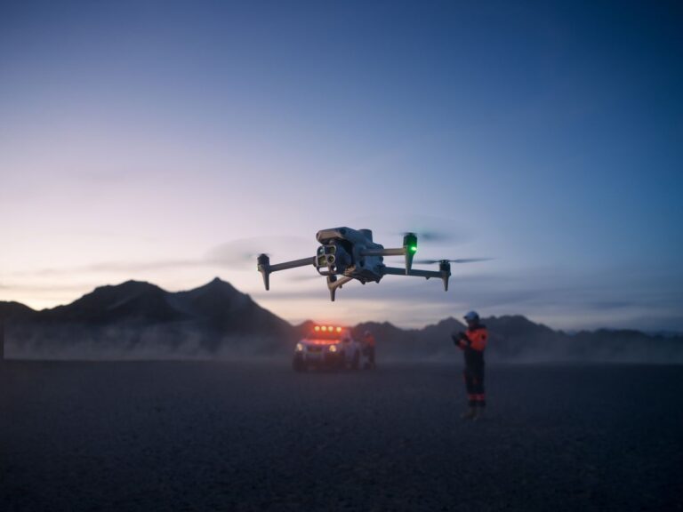 DJI Matrice 4T i lufta i skumringen med et utrykningskjøretøy og en redningsarbeider i bakgrunnen