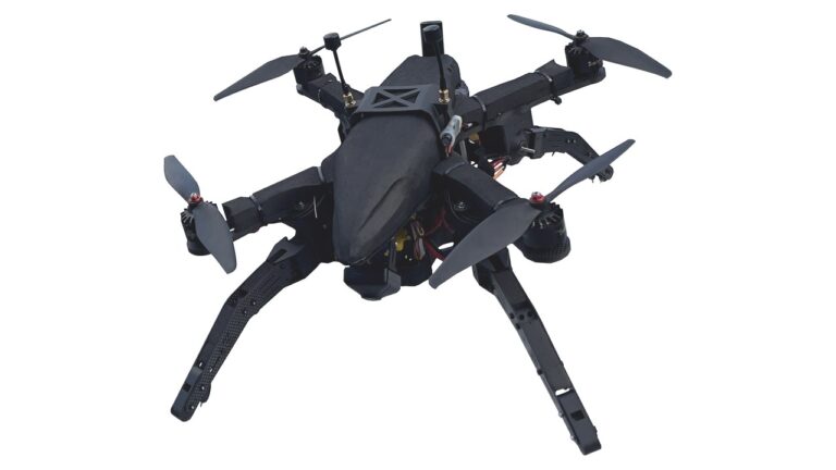 Svart firerotors drone med fire lange karbonfiberbein montert i X-mønster, fotografert mot hvit bakgrunn