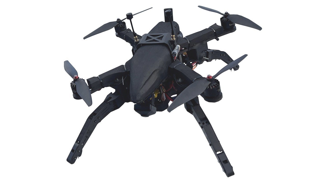 Svart firerotors drone med fire lange karbonfiberbein montert i X-mønster, fotografert mot hvit bakgrunn