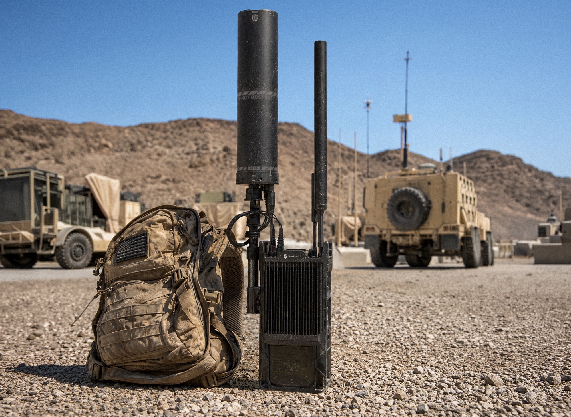 DroneShield RfRecon med to antenner stående ved en ryggsekk på en militær base i ørkenen