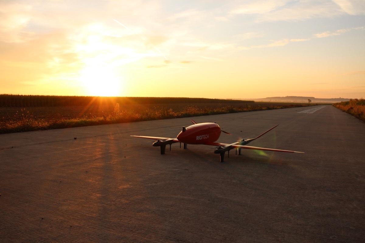 Rød RigiTech Eiger VTOL-leveringsdrone med fastvinge på en asfaltstripe i solnedgang