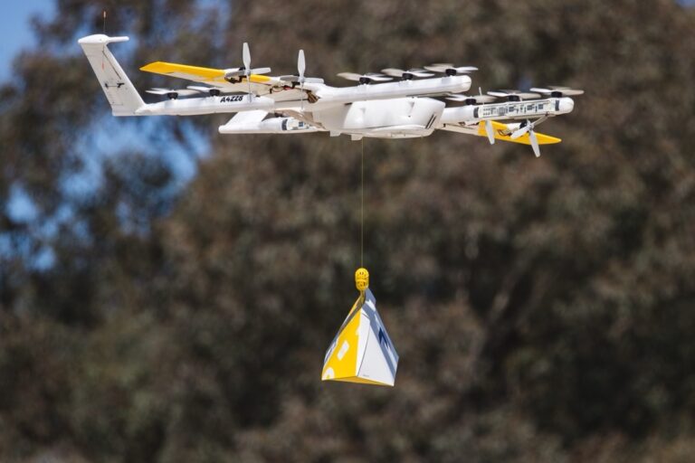 Wing-leveringsdrone i lufta med en pakke hengende i en line under seg
