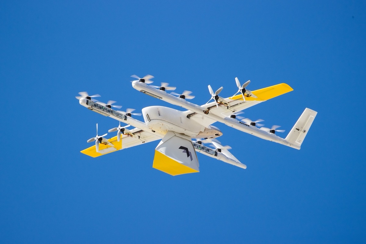 Wing-leveringsdrone med gule detaljer mot blå himmel