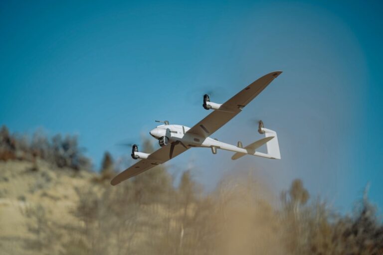 Quantum Systems Vector, en VTOL-fastvingedrone med fire løfterotorer, i flukt over et tørt gresslandskap